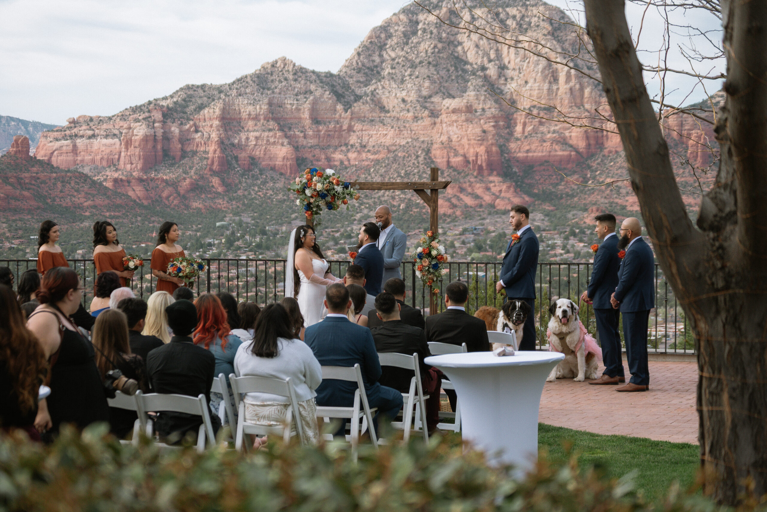 View of wedding ceremony and guests watching bride and groom while the wedding party stands on each side with two dogs in Sedona, Arizona