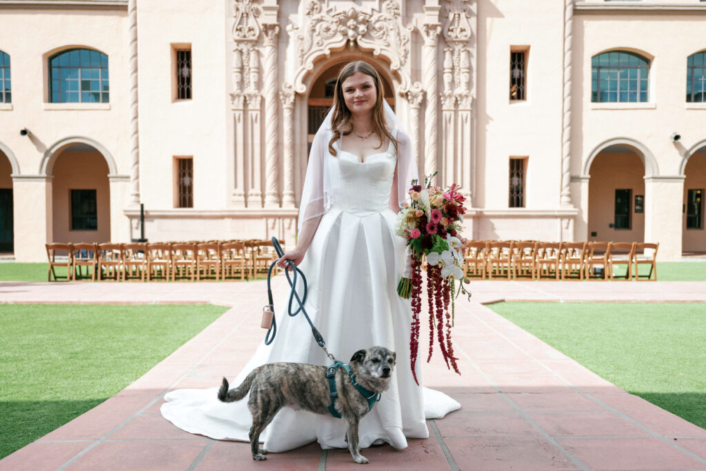 Including-My-Dog-On-My-Wedding-Day-7 Bride holding dog in one hand on leash while holding a bouquet in other hand and smiling at camera